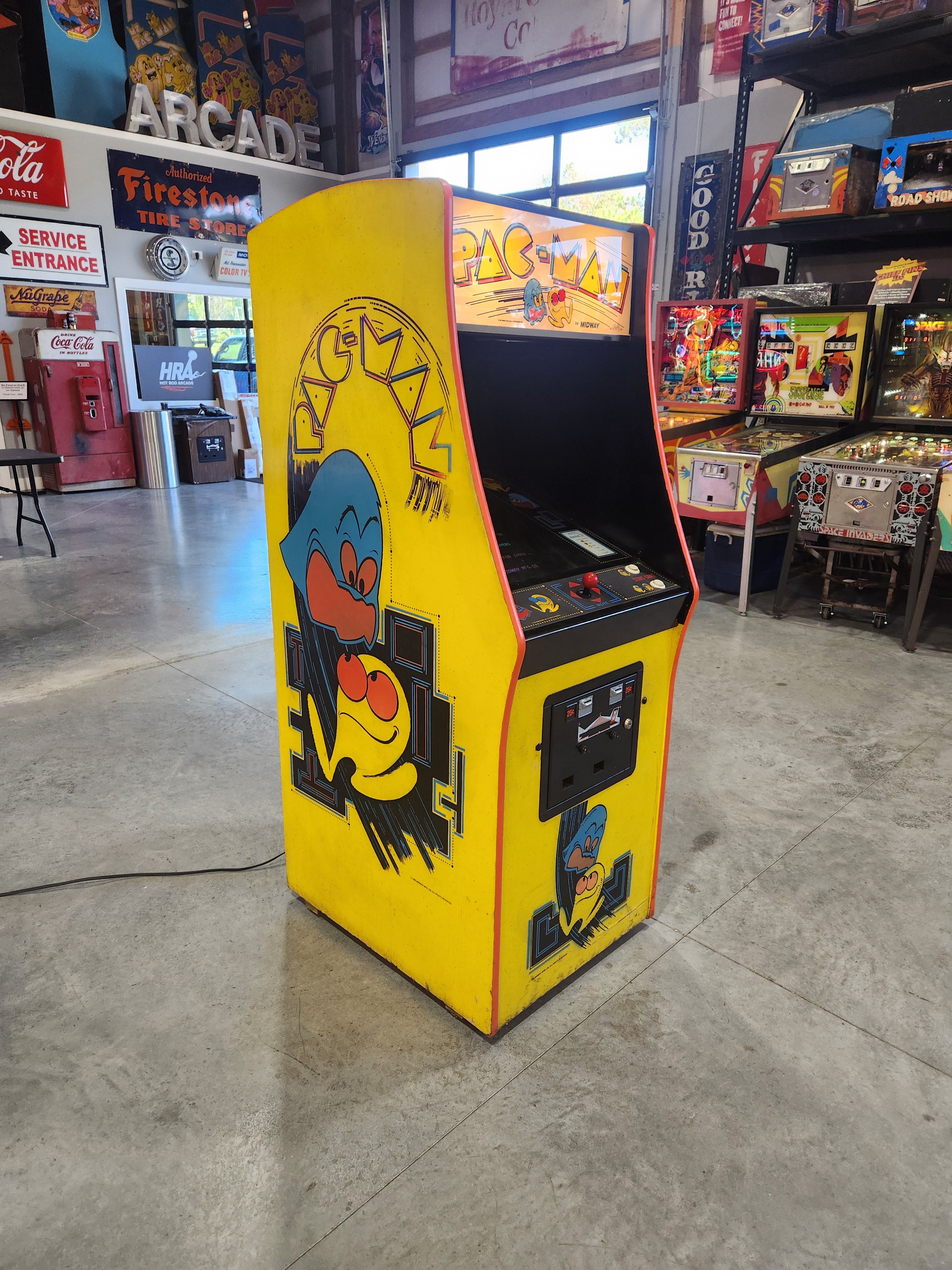 A restored original Pac-Man cabinet glowing inside a specialist retro arcade showroom.